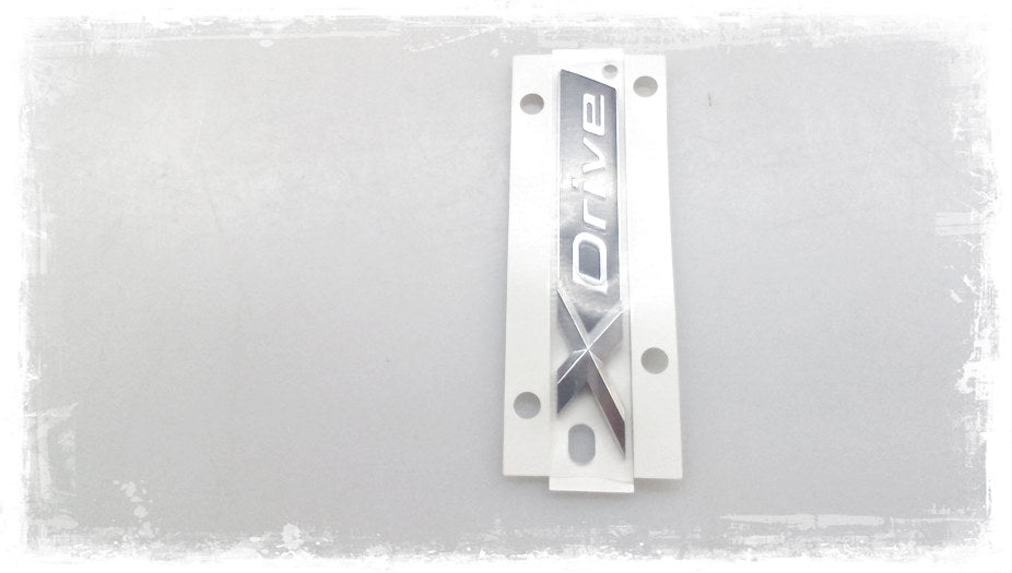 Emblema X-Drive OEM 51147437102 para BMW G31 (520d xDrive, 530d xDrive). Original BMW.