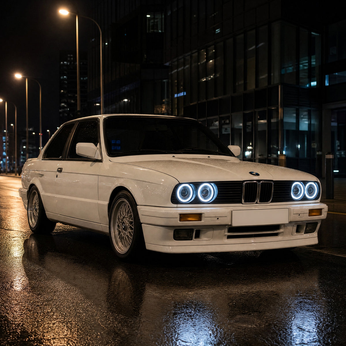 BMW Serie 3 E30 bianca a due porte, di notte, con angel eyes LED bianchi intorno ai suoi quattro fari tondi
