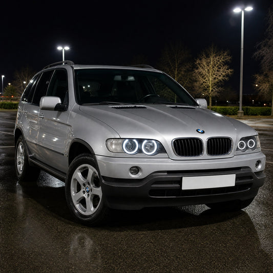 BMW X5 E53 anterior ao restyling, cinzento prateado, à noite, com angel eyes LED brancos: dois anéis acesos em cada farol