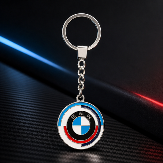 Llavero metálico para BMW con medallón circular tricolor, anilla y cadena corta sobre fondo negro grafito